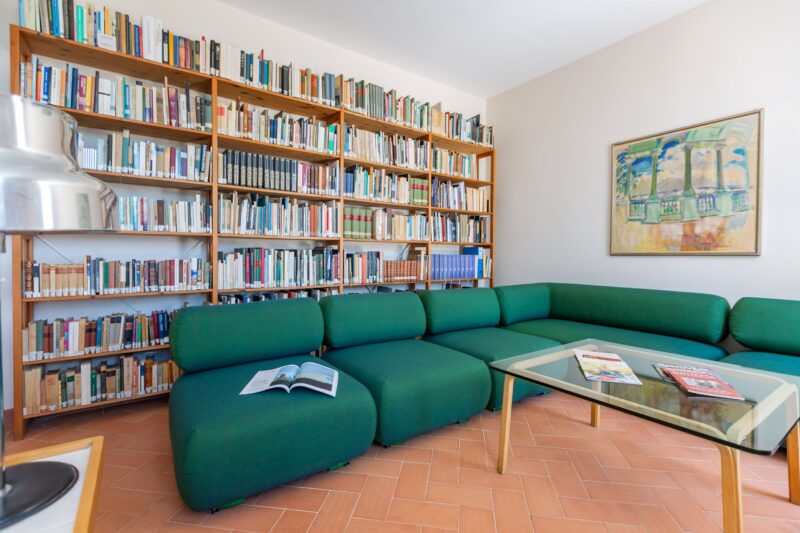 Kuva olohuoneesta, jossa kirjahylly ja vihreä sohva