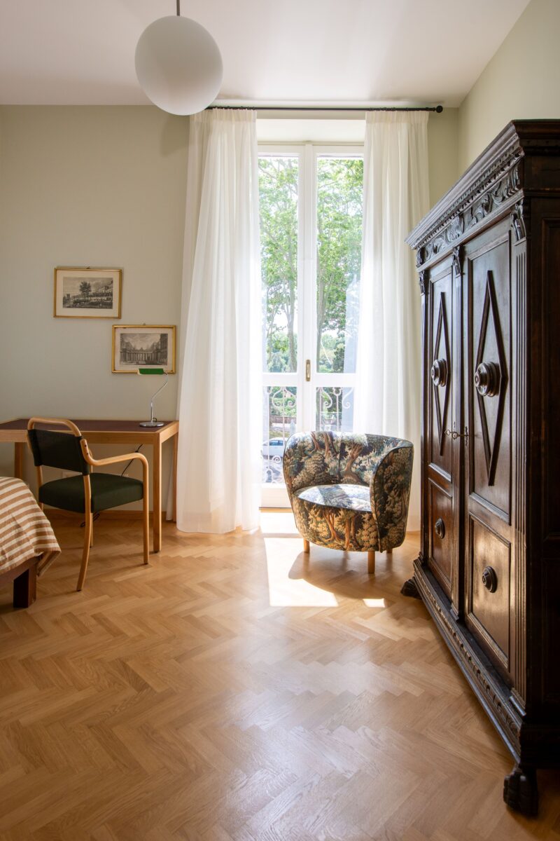 Kuva makuuhuoneesta, jossa sänky ja nojatuoli