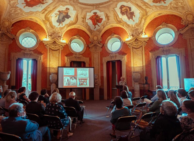 Kuva juhlasalista, jossa käynnissä esitelmä