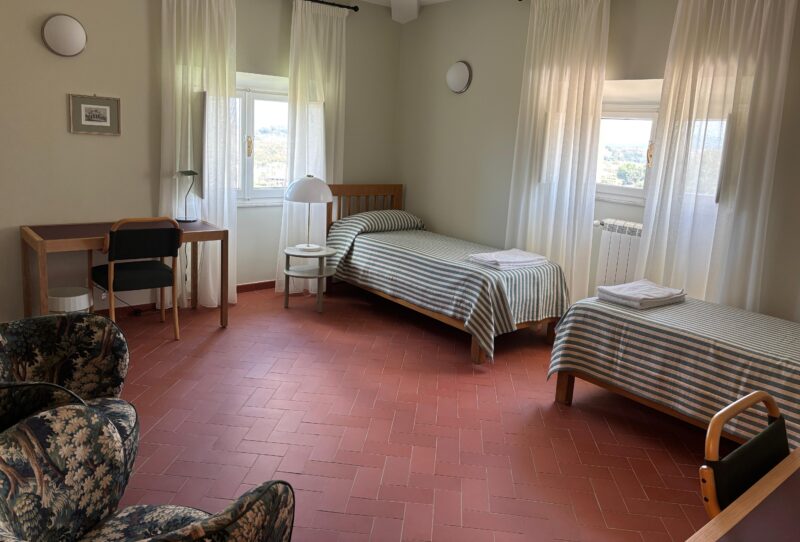 Valokuva kahden hengen residenssihuoneesta, josta löytyy mm. kaksi sänkyä, työpöydät ja verhoillut nojatuolit.