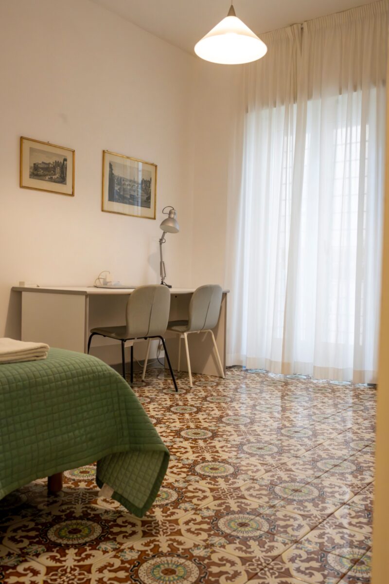 Via Faldan residenssihuone, josta löytyy mm. sänky ja työpöytä.