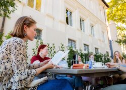 Opiskelijoita opiskelemassa huvilan puutarhassa