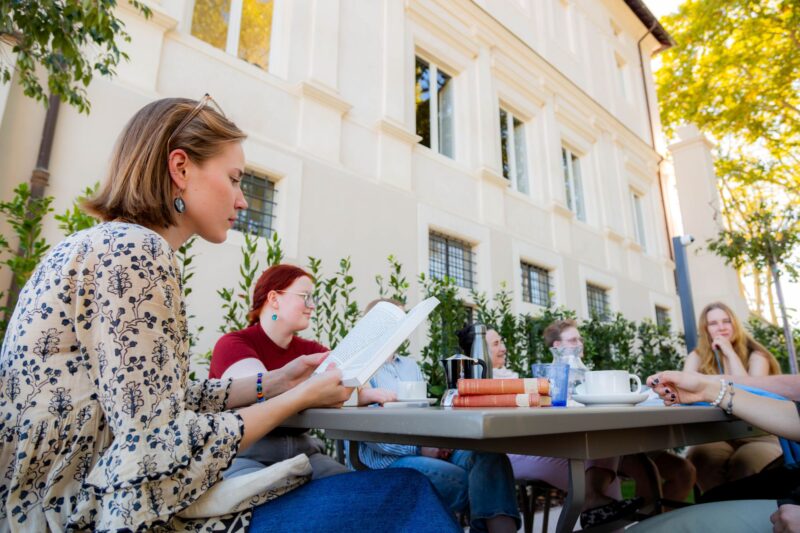 Opiskelijoita opiskelemassa huvilan puutarhassa