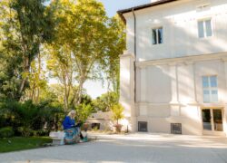 Opiskelija huvilan pihalla työskentelemässä tietokoneella