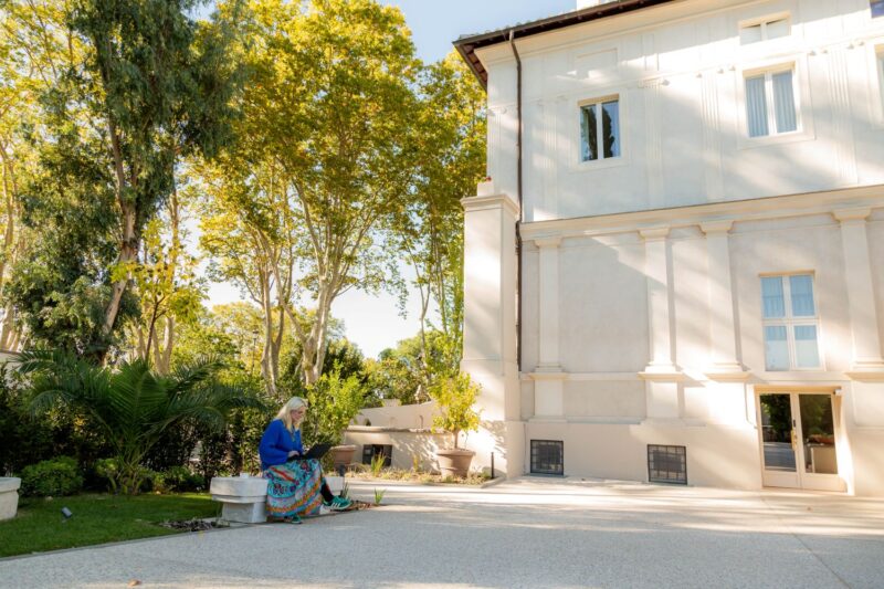 Opiskelija huvilan pihalla työskentelemässä tietokoneella