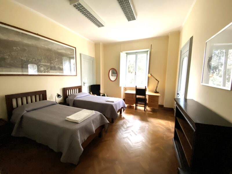 Huone, jossa kaksi sänkyä, kaappi ja kirjoituspöytä